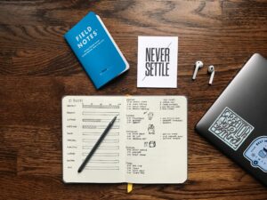 planner, books, laptop, earbuds on a wooden desk 