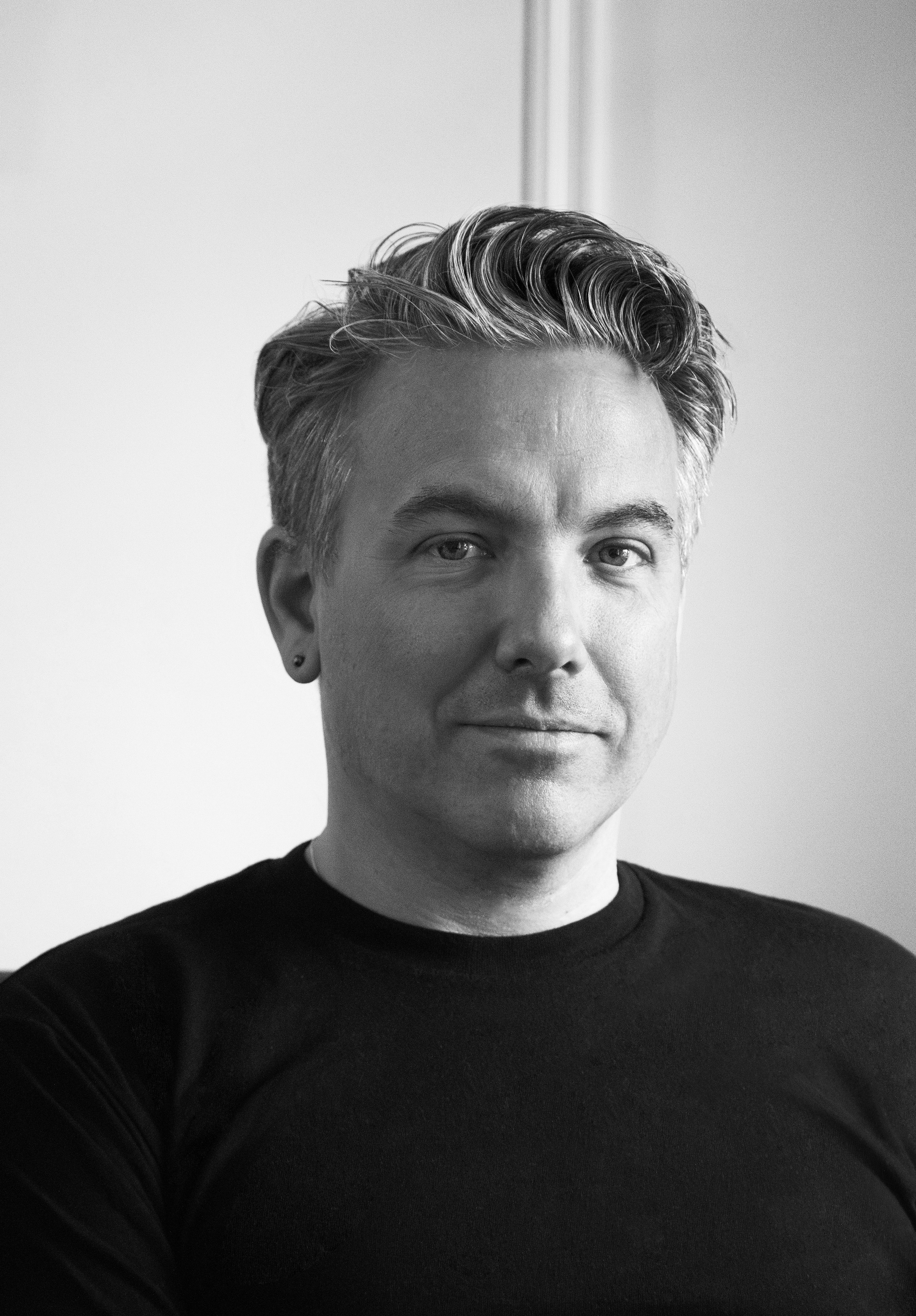 Portrait of a man in a black shirt against a white background