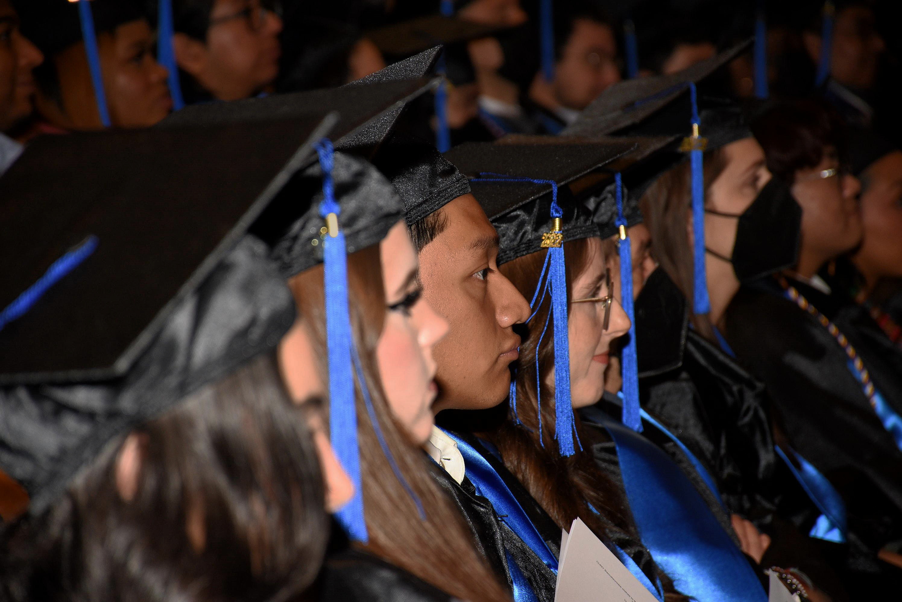 Side profile of CUNY BA graduates sitting in the auditorium watching the graduation ceremony