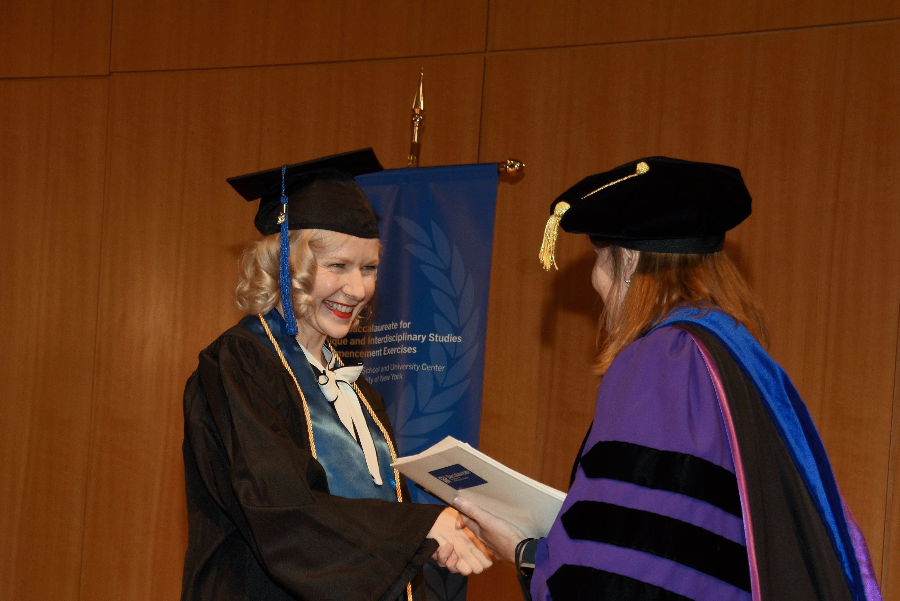 A graduate shaking hands on stage during 2024 Commencement