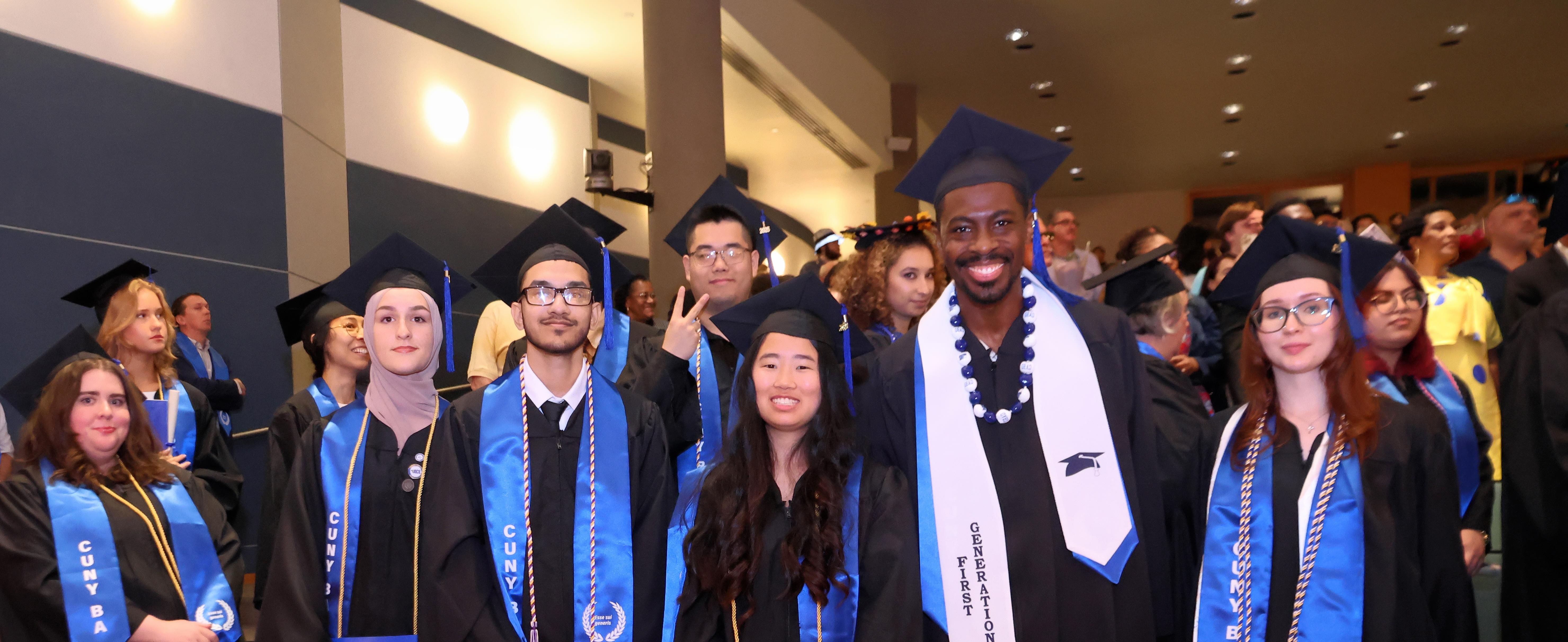 A group of CUNY BA graduates in caps and gowns posing for a group photo at their graduation ceremony