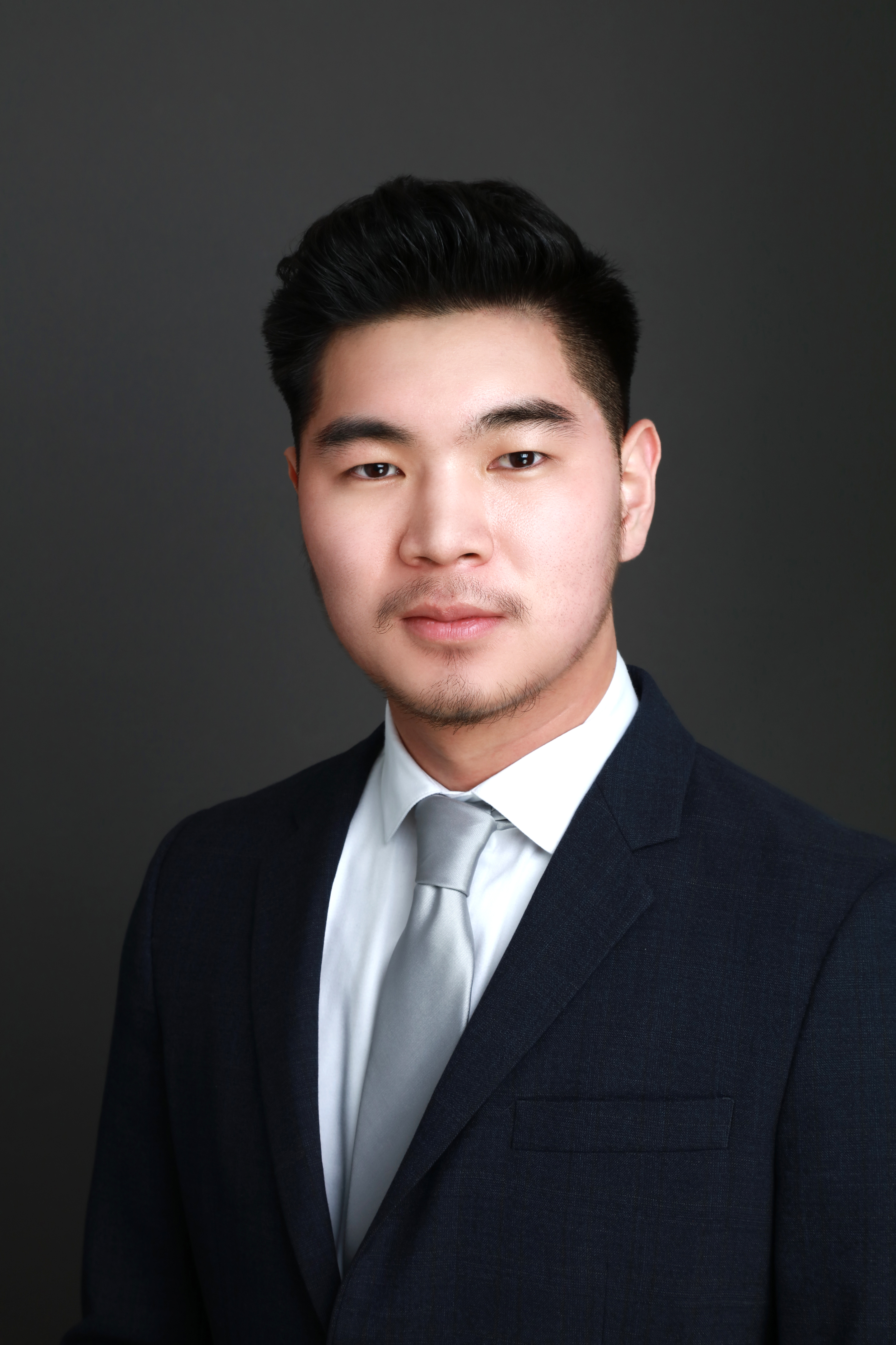 Headshot of Brandon Greyson Kim in a dark suit and light blue tie.