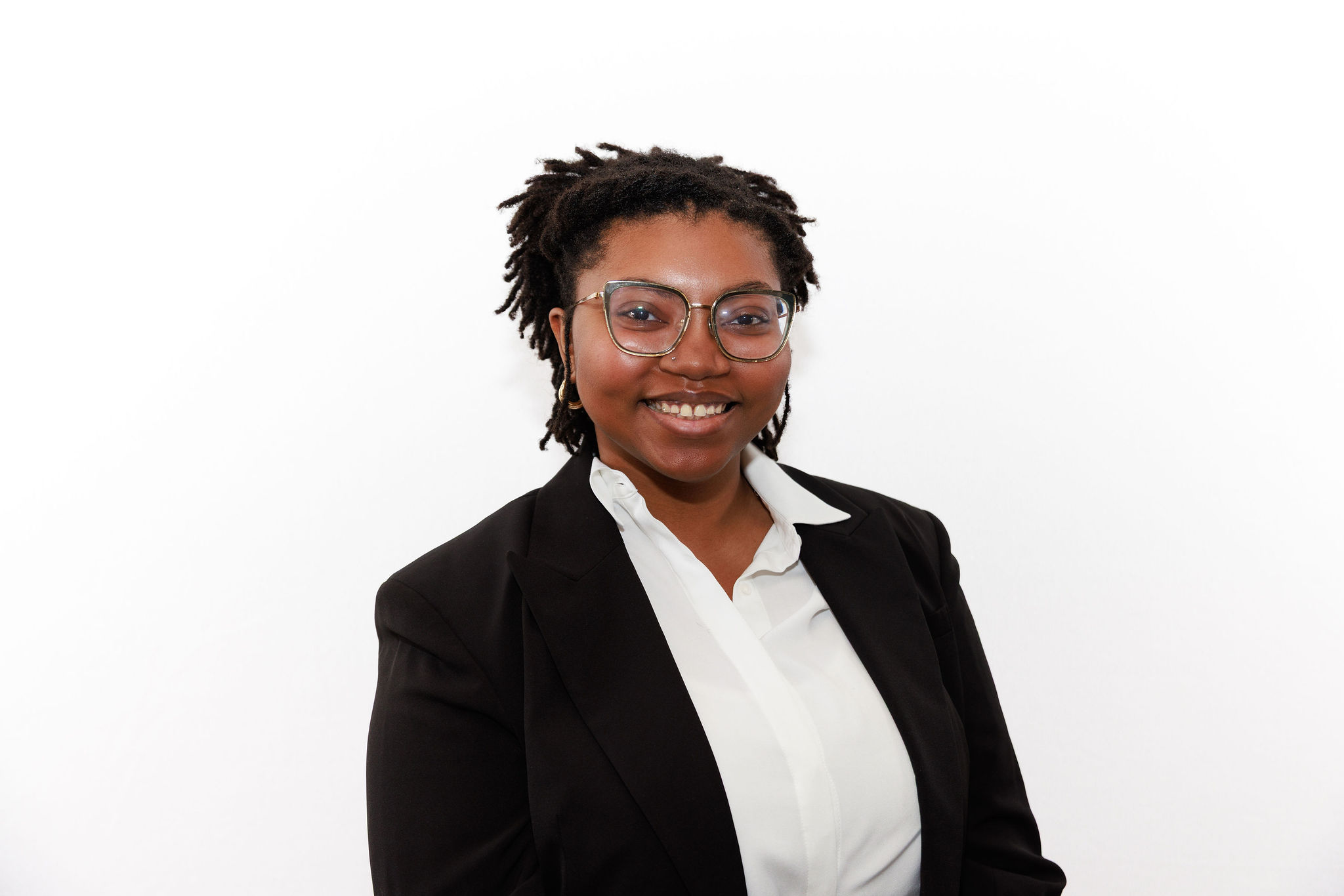 Portrait photo of a woman in a black blazer with a white button-down shirt against a white background.