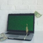 laptop with bills flying around