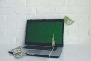 laptop with bills flying around